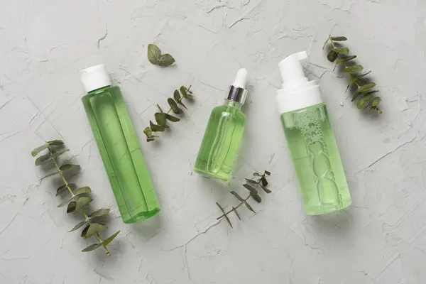 Herbal face care products on concrete background, top view