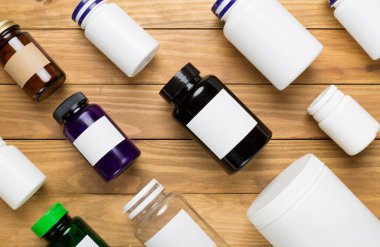 Ahşap zemin üzerinde vitaminler olan plastik şişeler.