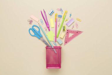 Renkli arka plan üzerinde okul kırtasiyesi olan pembe kalem tutucu, üst görünüm