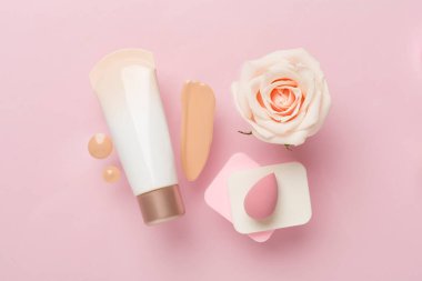 Renk arkaplanında makyaj temeli olan kompozisyon, üst görünüm