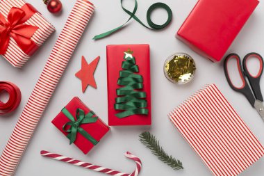 Kağıt kollu hediye kutuları ve renk arkaplanı üzerine noel süslemesi, üst görünüm