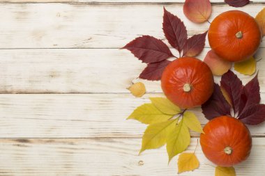 Tahta arka planda balkabakları, meyveler ve sonbahar yapraklarıyla yatıyordu.