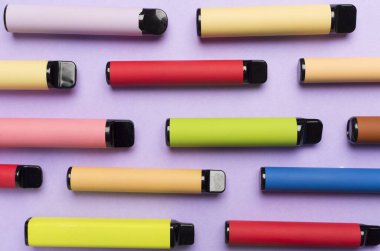 Disposable electronic cigarettes on color background, top view