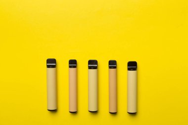 Disposable electronic cigarettes on color background, top view