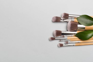 Natural biodegradable makeup brushes on color background, top view