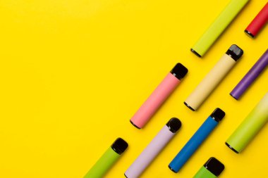 Disposable electronic cigarettes on color background, top view