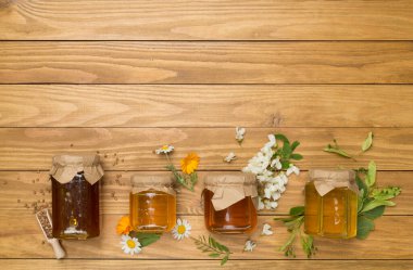 Ahşap zemin üzerinde farklı bal türleri olan kavanozlar, üst görünüm