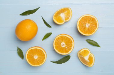 Flat lay with fresh oranges and leaves on wooden background.