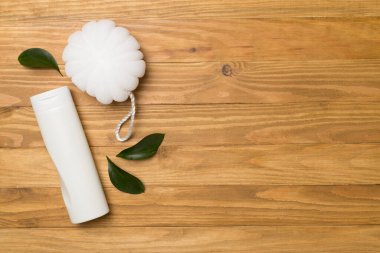 Shower gel with washcloth on wooden background, top view.