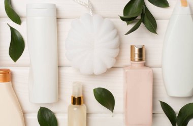 Different cosmetic bottles and washcloth on wooden background, top view