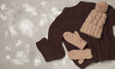 Sweater and winter hat withmittens on light background, top view