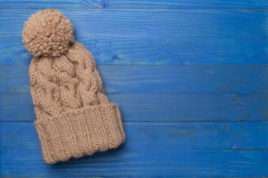Brown winter hat on wooden background. Top view