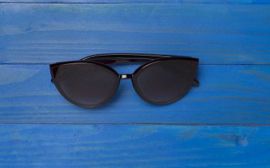 Ahşap zemin üzerinde güneş gözlüğü, üst görünüm.