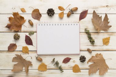 Ahşap zemin üzerinde defter ile sonbahar yaprakları, üst görünüm