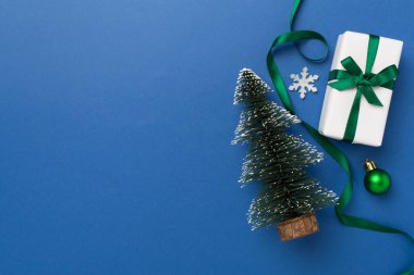 Arkaplanda hediye kutusu ve dekoru olan minyatür noel ağacı
