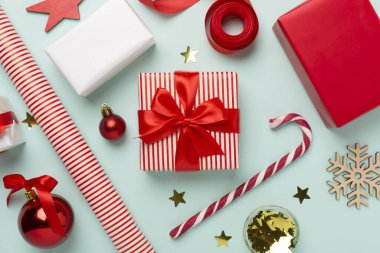 Kağıt kollu hediye kutuları ve renk arkaplanı üzerine noel süslemesi, üst görünüm