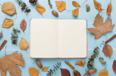 Ahşap zemin üzerinde defter ile sonbahar yaprakları, üst görünüm
