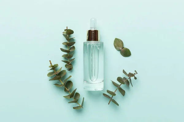 Herbal face serum on color background, top view