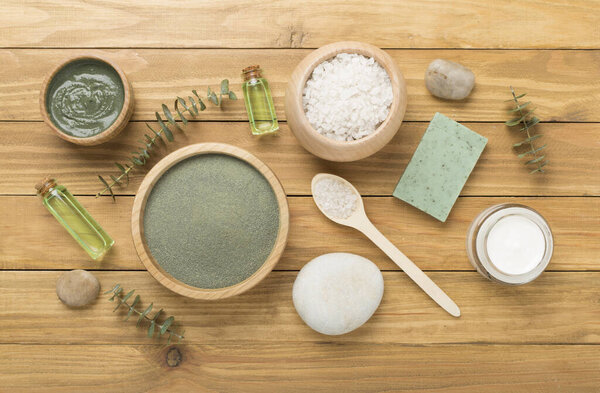 Composition with cosmetic clay and spa products on wooden background, top view