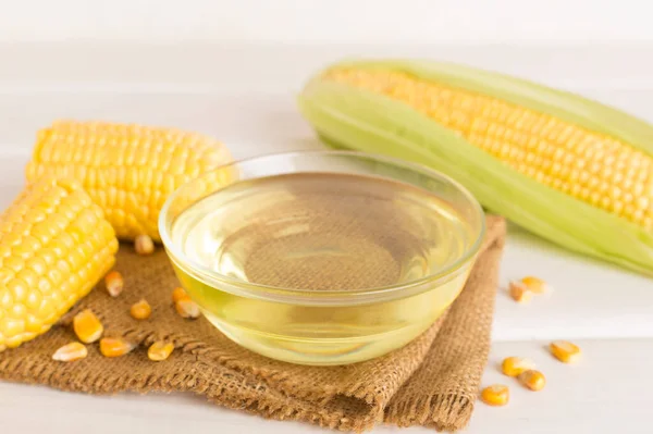 Corn oil with fresh cobs on wooden table