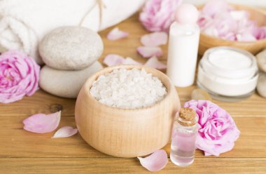 Ahşap masanın üzerinde pembe güller olan spa kompozisyonu