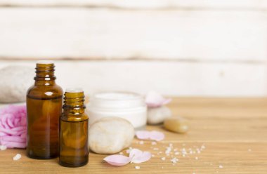 Ahşap masanın üzerinde pembe güller olan spa kompozisyonu