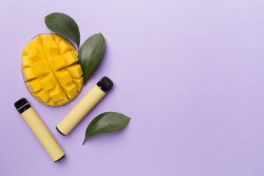 Renkli arka planda mango meyvesi olan tek kullanımlık elektronik sigaralar.