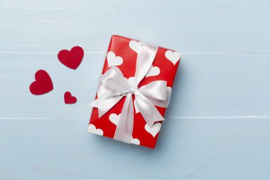 Gift box with hearts on wooden background, top view