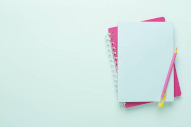 Renk arkaplanında kalem bulunan defterler, üst görünüm