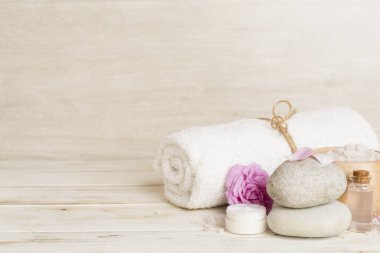 Ahşap masanın üzerinde pembe güller olan spa kompozisyonu