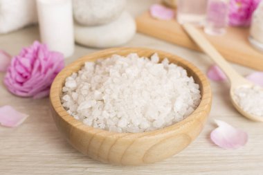 Ahşap masanın üzerinde pembe güller olan spa kompozisyonu