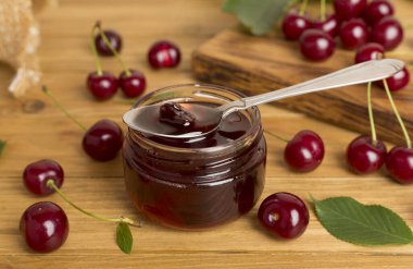 Ahşap masada ev yapımı kiraz reçelli kavanoz.