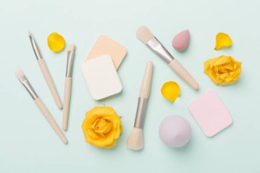 Renk arkaplanında makyaj fırçaları ve süngerler, üst görünüm