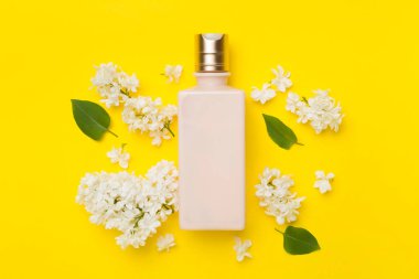 Renkli arka planda kozmetik şişesi ve çiçekli kompozisyon, üst görünüm