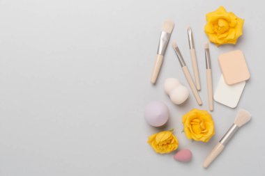 Renk arkaplanında makyaj fırçaları ve süngerler, üst görünüm