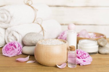 Ahşap masanın üzerinde pembe güller olan spa kompozisyonu