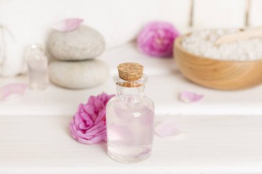 Ahşap masanın üzerinde pembe güller olan spa kompozisyonu