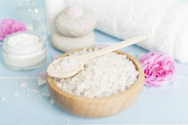 Ahşap masanın üzerinde pembe güller olan spa kompozisyonu