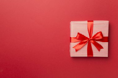 Renkli arka planda kırmızı kurdeleli hediye kutusu, üst görünüm.