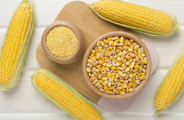 stock image Corn groats and seeds with fresh cobs on wooden background, top view