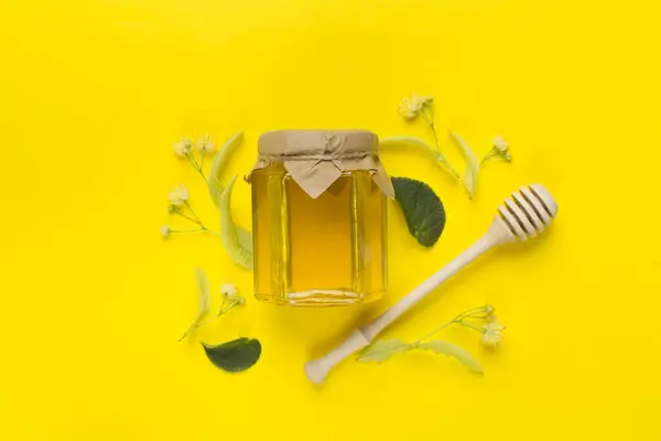 Linden honey with leaves and flowers on color backgroung, top view