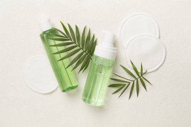 Köpüren yüz temizleyici ve beton arka planda eko pedleri olan mikiler suyu, üst görünüm.