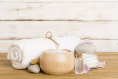 Ahşap masanın üzerinde pembe güller olan spa kompozisyonu