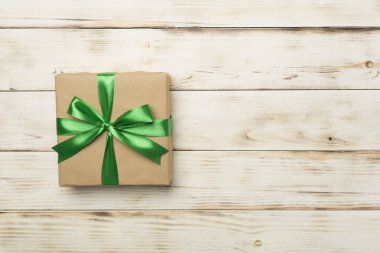 Yeşil kurdeleli hediye kutusu ahşap arka planda, üst manzara.