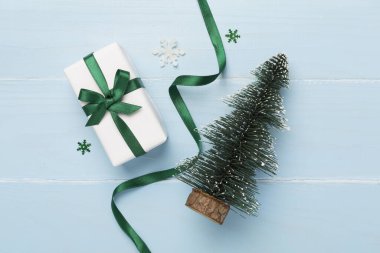 Minyatür Noel ağacı, hediye kutusu ve ahşap arka planda dekor.