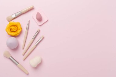 Renk arkaplanında makyaj fırçaları ve süngerler, üst görünüm