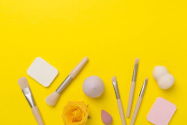 Renk arkaplanında makyaj fırçaları ve süngerler, üst görünüm