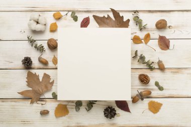 Ahşap zemin üzerinde sonbahar yaprakları olan tebrik kartı modeli, üst görünüm