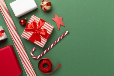 Kağıt kollu hediye kutuları ve renk arkaplanı üzerine noel süslemesi, üst görünüm