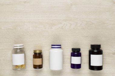 Ahşap zemin üzerinde vitaminler olan plastik şişeler.